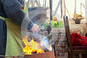 Close-up of blacksmith manually forging the molten metal on the anvil in smithy workshop.