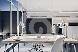 Close up of blank mock up computer monitor on wooden office desktop in modern interior. Workplace concept.