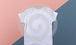 Close up of blank, white baby bodysuit template on a pink and blue background