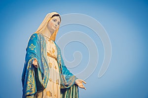 Close-up of the blessed Virgin Mary statue figure. Catholic praying for our lady - The Virgin Mary. Blue sky copy space on