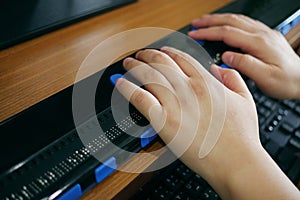 Close-up blind person hands using computer with braille display or braille terminal a technology assistive device for persons with