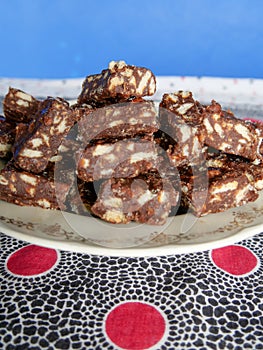 Close-up of blocks of chocolade brownie and biscuit sweets stacked on top of each other on a plate. Vertical image