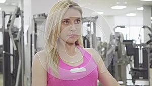 Close-up of blond concentrated sportswoman pulling equipment in gym. Beautiful Caucasian woman with hazel eyes