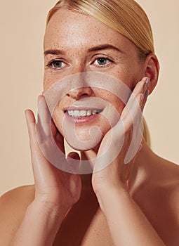 Close up of blond female touching her freckled skin