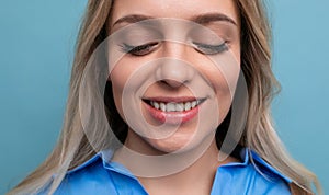 close-up of a blond young woman cutely closing her eyes on a blue background