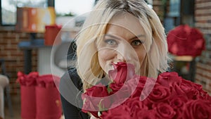 Close up of blonde attractive woman smelling bouquet with red roses