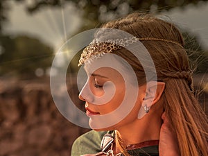 Close-up of blonde girl with blue eyes and elf ears wearing a green cape