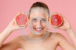 Close up blonde half naked woman 20s perfect skin nude make up blue eyes hold in hand grapefruit isolated on pastel pink