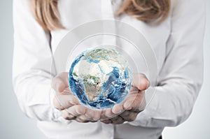 Close-up of blonde's hands who holds the globe with Africa, Europe and Asia hemisphere. A woman dressed in formal clothes. A light