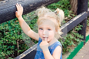 Close up Blondy toddler baby girl, looking at camera and putting her finger into her mouth - one of the most commonly seen behavio