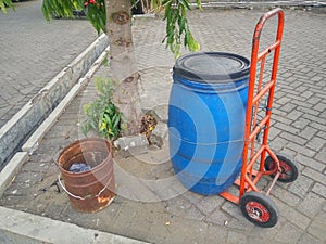 Close up on a blue barrell garbage can beside a tree