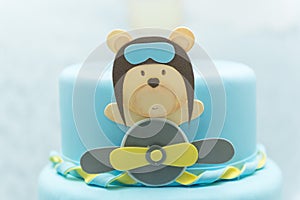 Close up of blue cake decorated with cute aviator bear, plane and clouds