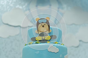 Close up of blue cake decorated with cute aviator bear, plane and clouds