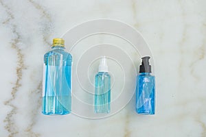 Close-up of Blue Ethyl alcohol in spray bottle, plastic bottle and gel bottle, on the marble desk. For coronavirus protection