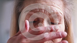 Close up on blue eyes of an elderly woman with wrinkled skin. Depression at old age