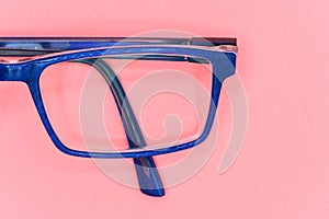 Close up of Blue glasses on pink background, top view.