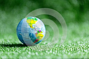 Close up of blue globe on green grass on green blur nature background, earth day or world environment day concept. Green world and