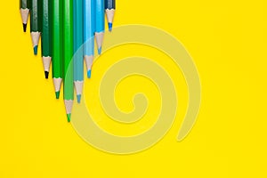 A close up of blue, greeen pencils on the yellow background
