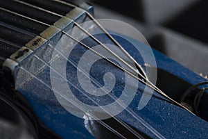 Close-up of blue guitar headstock with a lot of dust and damaged strings