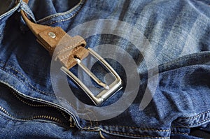 Close-up of blue jeans with a brown leather belt