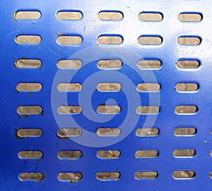 Close up of a blue metal bench with holes pattern.