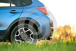 Close up of blue off road car on green grass. Traveling by auto, adventure in wildlife, expedition or extreme travel on a SUV