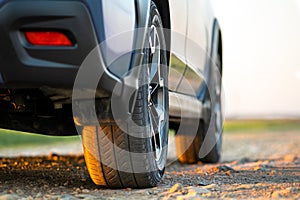 Close up of blue off road car wheel on gravel road. Traveling by auto, adventure in wildlife, expedition or extreme travel on a