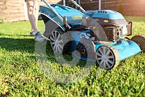 Close-up blue push lawn mower on a green grass