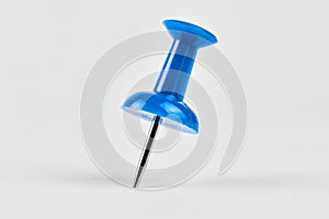Blue pushpin standing upright on a white surface