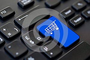 Close up of a blue return key with a shopping cart icon on computer