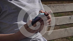 Close-up of a blue smartphone in the hands of a teenager on the street.