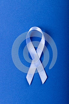 Close-up of blue stomach cancer awareness ribbon isolated over blue background, copy space