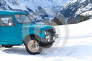 close-up of a blue SUV with iron chains on wheels against the background of the Alpine mountains, the concept of the safety of