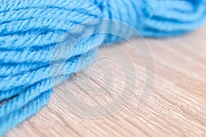 Close up of a blue yarn ball on a wooden table with free space for text, soft selected focus