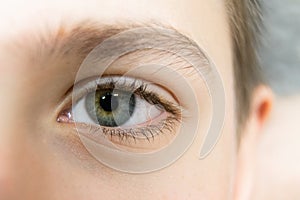 Close-up of the bluish-green eyes of a teenager. A young man with a light skin color has beautiful eyes. Selective focus