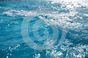 Close-up blur of blue water surface with sunlight