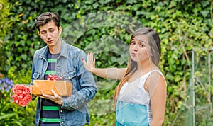 Close up of blurred man holding a gift and flowers with shocked face after see his girlfriend stretching her arm