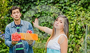 Close up of blurred man holding a gift and flowers with shocked face after see his girlfriend stretching her arm