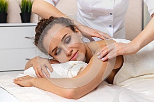 Close-up body care in spa salon for young woman, beautiful girl with closed eyes enjoying treatment procedure and back massage,