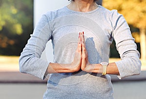 Close up of body woman doing namaste gesture outdoors