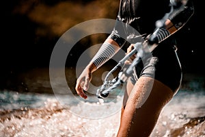 Close-up of body of woman in wetsuit who holds rope and ride on waves