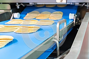 Close up bologna sliced plate on conveyor of automatic slicer machine for industrial food manufacture