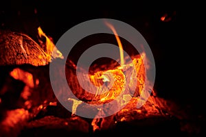 Close up of bonfire with a sparks at night. Heat from burning logs and coals in the dark