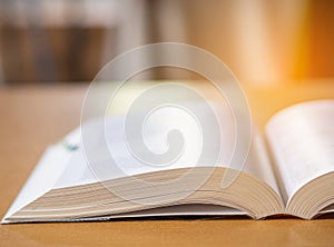 Close-up of book open on desk with sunlight effect blur background