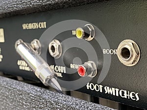 Close-up the boost input jack of a back control panel electric guitar amplifier with blurred another control panel black