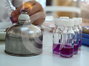 Close-up of bottle being sterilized with an alcohol burner before use in bacterial cultures. Medicine and microbiology concept