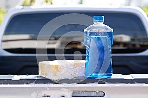 Close up bottle of car wash soap with yellow sponge for washing, selective focus