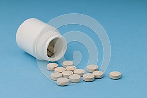 Close Up Of Bottle Of Homeopatic Tablets On blue  Background . nutrition supplements, grey multivitamin pills