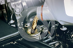 Close up of a bottle of motor oil being poured into a car combustion engine for lubricate. Oil change in car engine