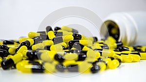 Close up on a bottle of prescription drugs falling out. Black and yellow pills